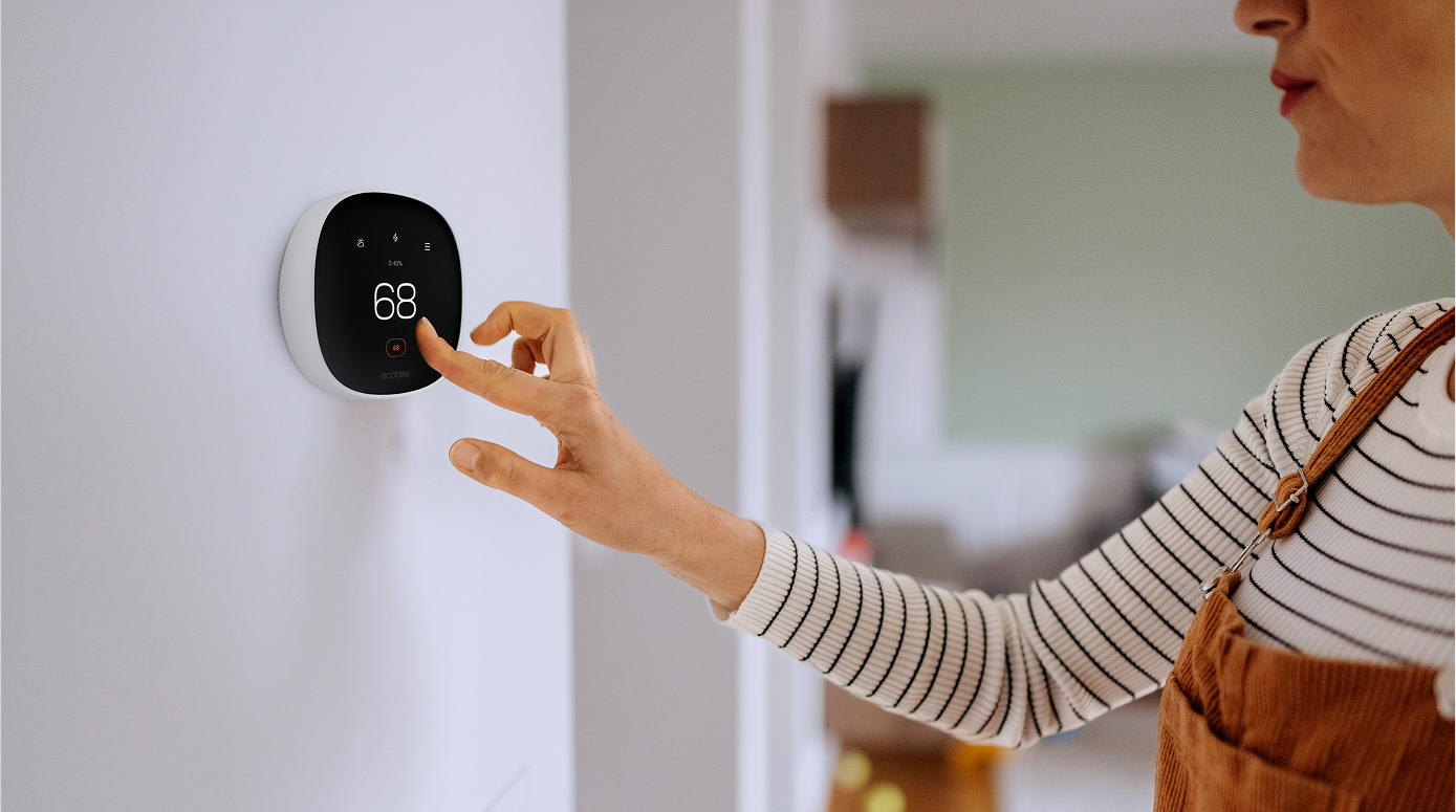 home owner changing the temperature on her smart thermostat